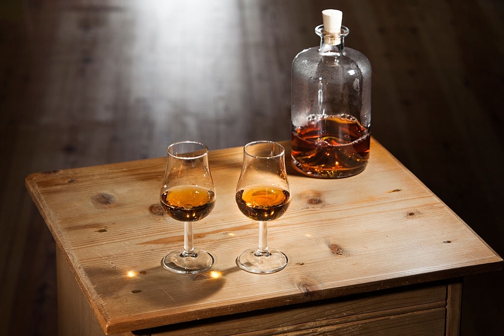 Bottle and two glasses of brandy on a vintage wooden table